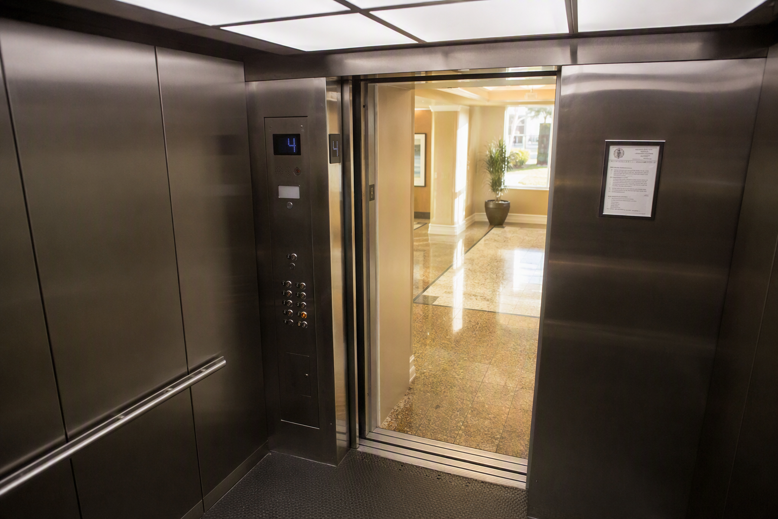 Florida Elevator Inspection Compliance Inside a Modernized Cab Modernized elevator cab interior with brushed stainless walls, LED ceiling, and Florida state inspection certificate placard in a Sarasota mid-rise residential building