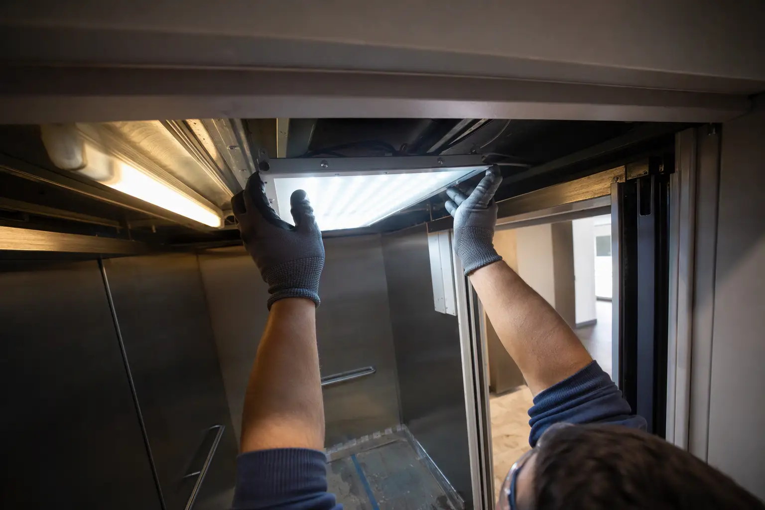 LED Cab Lighting Retrofit in Commercial Elevator Elevator technician installing LED cab lighting retrofit inside a Florida commercial elevator cab replacing older fluorescent fixtures to reduce energy consumption
