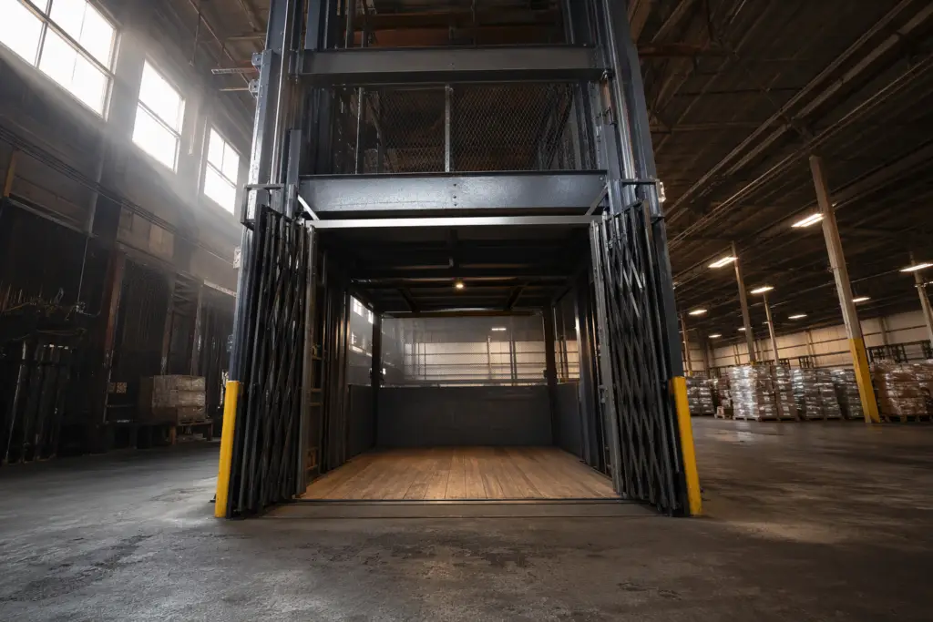 Heavy-duty freight elevator with steel bi-parting gate inside a Florida warehouse building, illustrating Florida freight elevator maintenance and safety requirements for industrial facilities